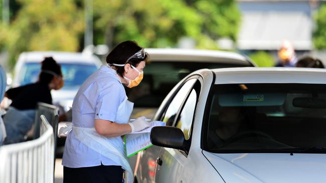 The Townsville Hospital and Health Services health worker wears a plastic apron, but has her arms exposed at the Reid Park drive through COVID-19 testing clinic.