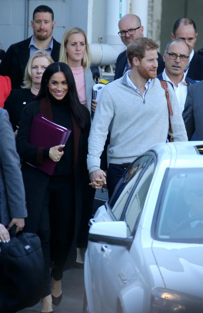 Meghan nailed “travel chic” with slim-fitting black pants, a black top, and long black and burgundy coat. Picture: John Grainger