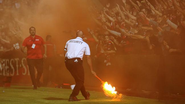 A security guard grabs a flare lit by fans during the A-League match between Sydney FC and Western Sydney Wanderers at Jubilee Stadium last Friday night. Picture: AAP