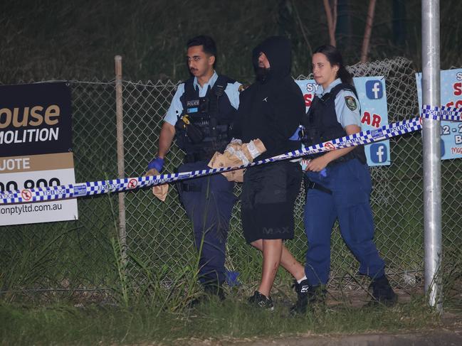 Samimjan Azari, who was inside the car that was shot at, is led away from the crime scene at Granville under the M4 overpass. He has since been charged with firearm offences. Picture: Rohan Kelly