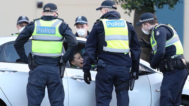 Police swarm the car of a woman at public housing on Racecourse Rd in Flemington which have been locked down by the Victorian Government in an attempt to stop the outbreak of COVID-19. Picture: David Crosling