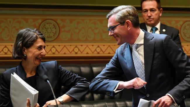 NSW Premier Gladys Berejiklian bumps elbows with NSW Treasurer Dominic Perrottet as she congratulates him after delivering the budget. Picture: AAP