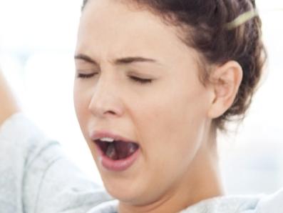 Full length of female entrepreneur yawning while stretching at desk in office. Horizontal shot.