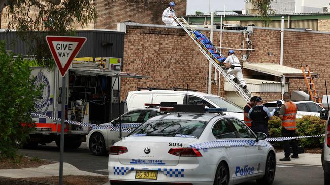 Emergency workers remove a body is taken off the roof of an arcade at Engadine this afternoon after a worker was electrocuted.