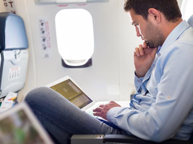 Casually dressed middle aged man working on laptop in aircraft cabin during his business travel. Photo: istock