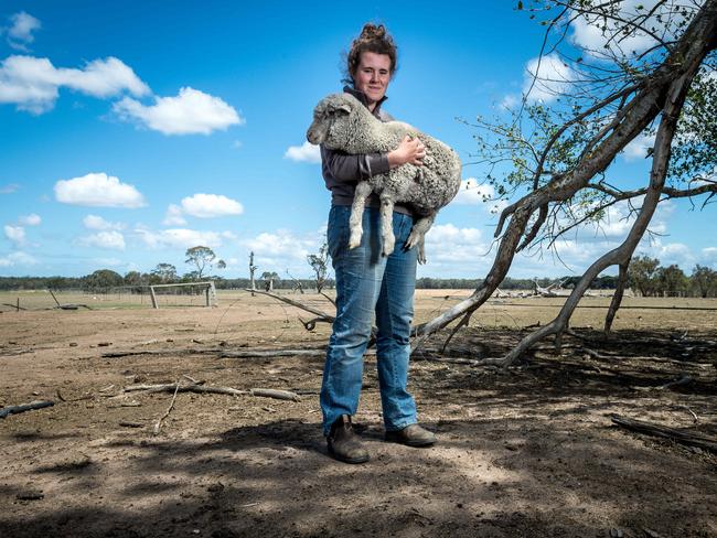 Megan Harrison holds a lamb on her drought-affected property in Giffard West. Picture: Jake Nowakowski