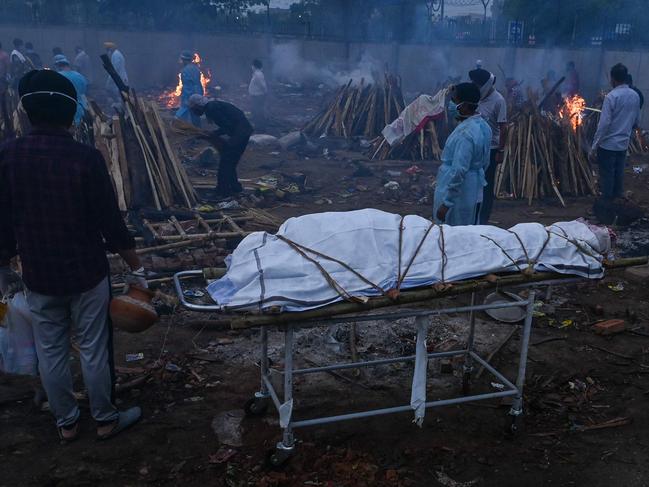 A relative waits next to the body of his who died from COVID-19 at a cremation ground in New Delhi. Picture: Prakash Singh