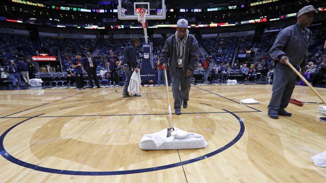 Workers mop the court during a delay for the start of an NBA basketball game against the Indiana Pacers in New Orleans.