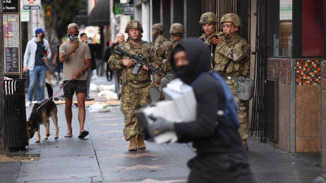 A looter carrying boxes of shoes run past National Guard soldiers in Hollywood, California. Picture: AFP