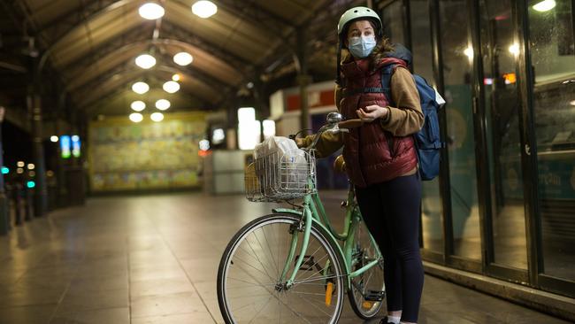 Turkish student Aynur Cargantries tries to get home with a flat tyre on her bike as the 8pm curfew approaches in Melbourne on Sunday. Picture: Paul Jeffers