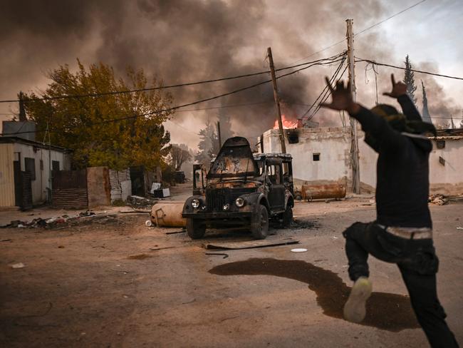 A man gestures as people loot the Najha military housing complex in southeast Damascus. Picture: AFP