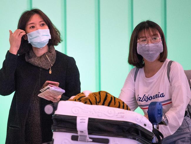 Passengers wear face masks to protect against the spread of the Coronavirus as they arrive on a flight from Asia at Los Angeles International Airport, California, on January 29, 2020. - A new virus that has killed more than one hundred people, infected thousands and has already reached the US could mutate and spread, China warned, as authorities urged people to steer clear of Wuhan, the city at the heart of the outbreak. (Photo by Mark RALSTON / AFP)