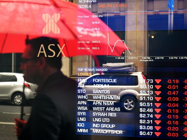 A man is seen in a reflection to stop to look at the electronic share board at the Australian Stock Exchange (ASX) in Sydney, Monday, Aug. 24, 2015. The ASX 200 has dipped below 5100 points for the first time in 18 months, as the big banks continue to bear the brunt of fear selling and with the big miners also getting hit on continued weakness in commodity prices. (AAP Image/Dan Himbrechts) NO ARCHIVING