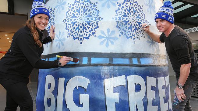 Artist Vincent Fantauzzo puts his finishing touches to the giant beanie in the Bourke Street Mall with Bec Daniher. Picture: Ian Currie