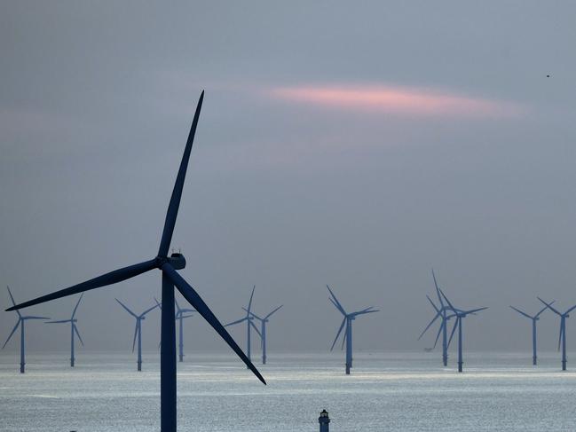 (FILES) In this file photo taken on May 14, 2019 New Brighton lighthouse is pictured at sunset, in New Brighton, at the mouth of the river Mersey, in north-west England on May 14, 2019, with the Burbo Bank Offshore Wind Farm visible on the horizon. - Britain, a global leader in offshore wind energy, plans to make the sector one of the pillars of its transition to carbon neutrality in the coming decades. The country aims to quadruple its offshore electricity production capacity by 2030 by utilising the windswept North Sea and a favourable policy environment. (Photo by Paul ELLIS / AFP)