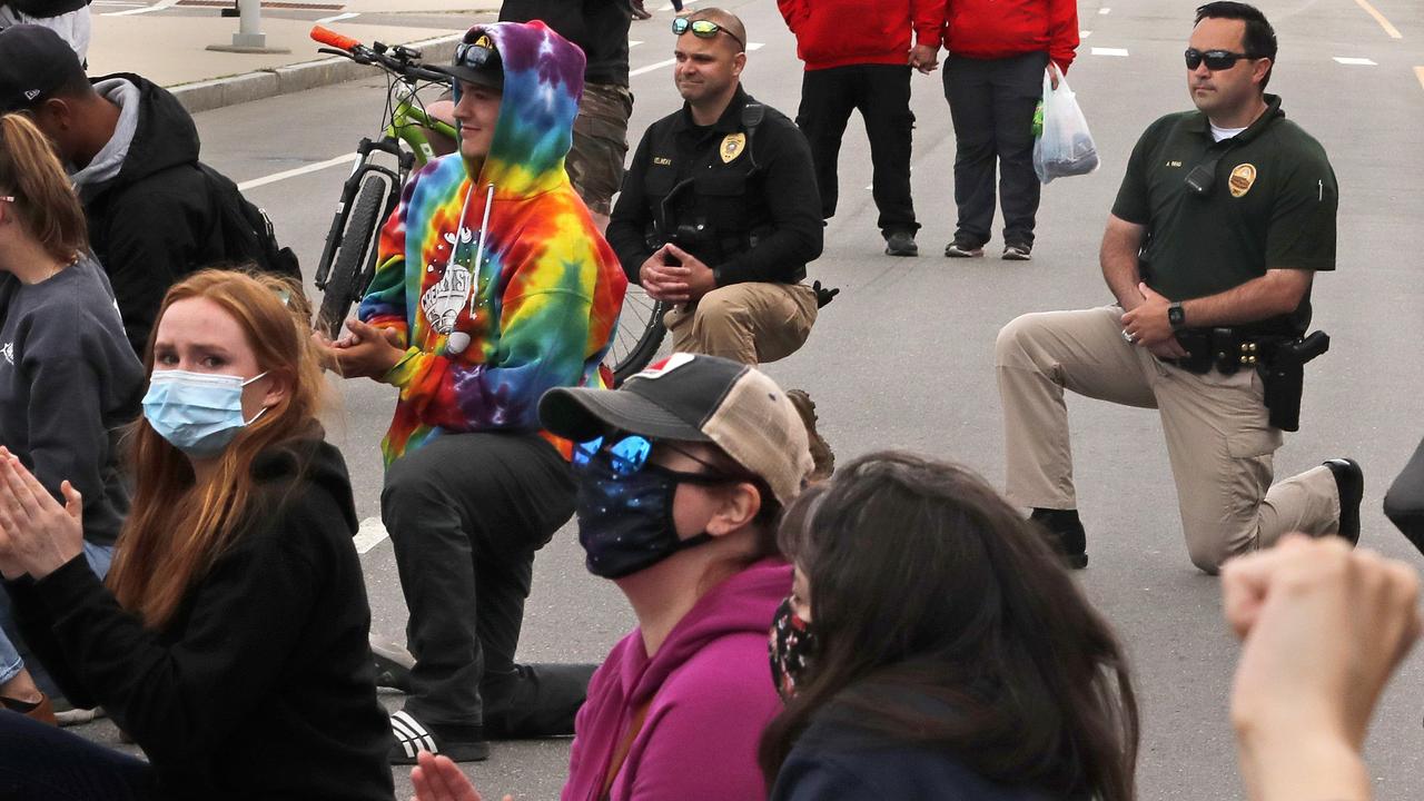 Hampton Lieutenant Alex Ren and Seabrook Deputy Chief Kevin Gelineau take a knee as they join protesters against police brutality on Hampton Beach. Picture: Charles Krupa/AP