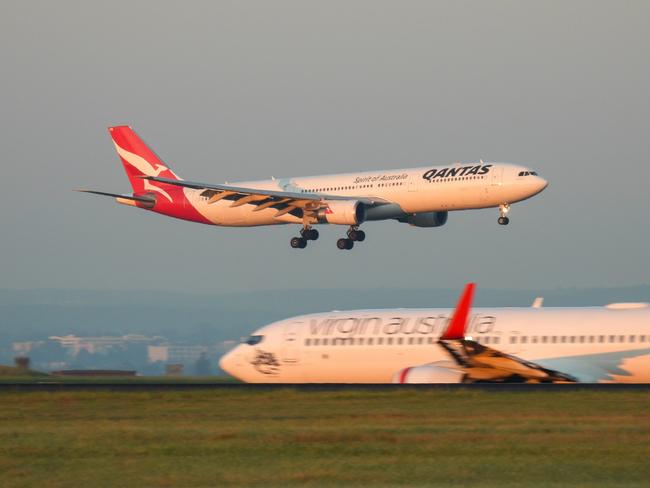 A Qantas Airbus A330-303 plane, registration VH-QPB, coming into land from the south on the main runway of Sydney Kingsford-Smith Airport as flight QF128 from Hong Kong. In the foreground is a Virgin Australia Boeing B737-8FE plane, registration VH-YFZ, taxiing before departure as flight VA1528 to Hobart.  This image was taken from Mill Stream Lookout, Botany Bay on a sunny morning at sunrise on 30 March 2024.27 October 2024Kendall HillPhoto - iStock