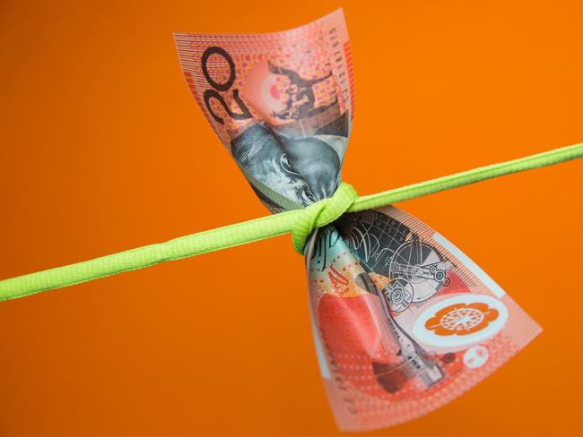 Australian twenty dollar note tied in a knot on a plain background, money generic squeeze pressure