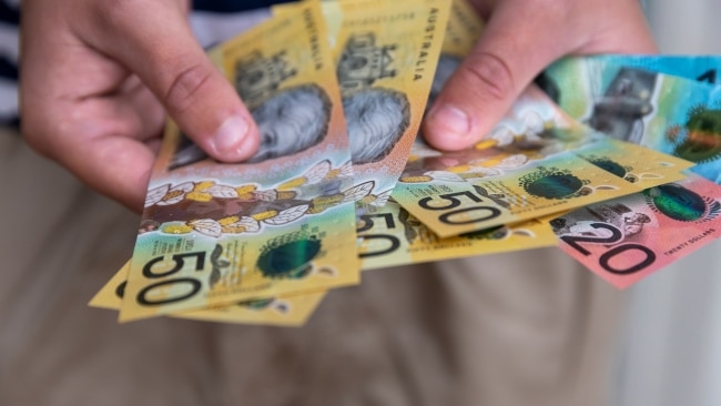 Male person holding some Australian currency. This visual concept evokes ideas around saving money, paying for expenses and investments.