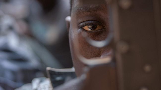 A newly released child soldier looks through a rifle trigger guard during a release ceremony for child soldiers in Yambio, South Sudan. Picture: AFP PHOTO / Stefanie Glinski