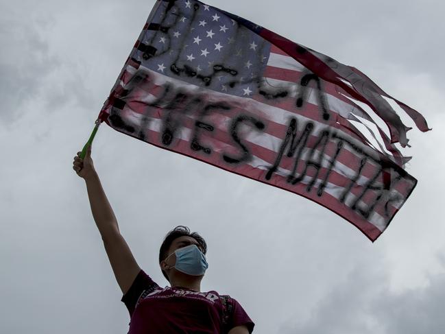 Erik Ventura of Washington, waves an American flag with "Black Lives Matter" spray painted on it on 16th Street Northwest renamed Black Lives Matter Plaza near the White House in Washington, Friday, June 19, 2020, on Juneteenth, the holiday celebrating the day in 1865 that enslaved black people in Galveston, Texas, learned they had been freed from bondage, more than two years after the Emancipation Proclamation. (AP Photo/Andrew Harnik)