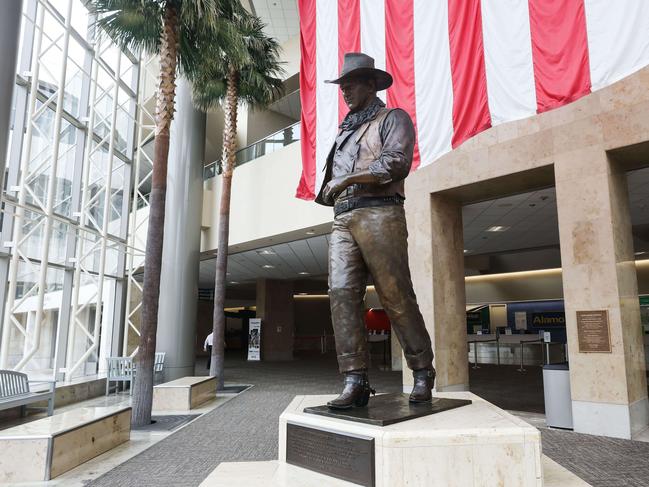 A statue of John Wayne is on display beneath an American flag in John Wayne Airport, located in Orange County, California. Picture: Getty Images/AFP