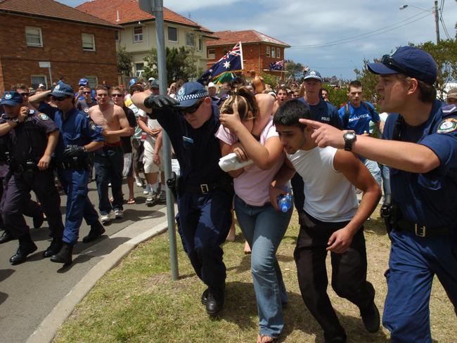 Police try to protect young couple of Middle Eastern appearance as they are followed by the angry mob.