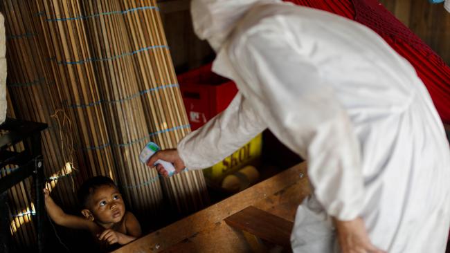 A wealth worker measures the temperature of a toddler at the Pindobal community in the Igarape-Miri municipality, lower Tocantins region, northeast of Para state, Brazil. Picture: AFP