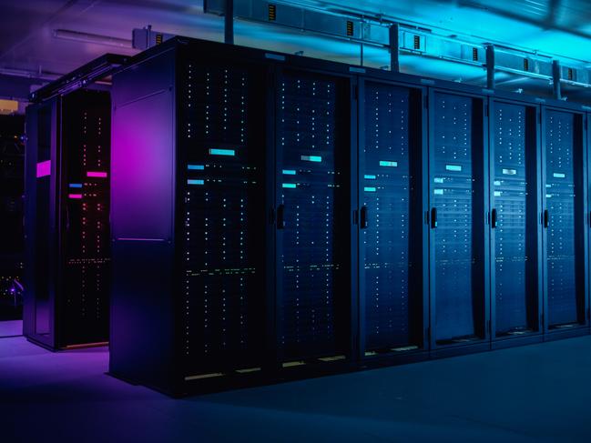 In Data Center: IT Technician Running Maintenance Programme on Laptop, Controls Operational Server Rack Optimal Functioning. Modern High-Tech Telecommunications Operational Data Center in Neon Lights.