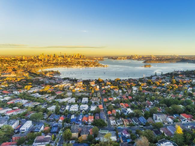 Wealthy Eastern suburbs of Sydney city around Harbour in aerial view with soft morning light and blue sky. Australian housing generic