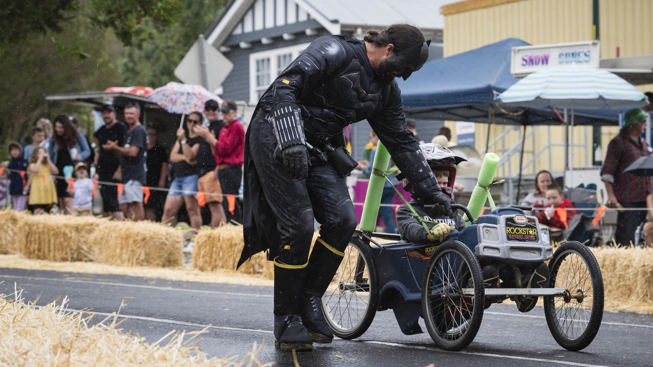 Batman aka Doug Gale assists a young racer down the track at the Greenmount Billy Cart Challenge, Saturday, November 25, 2023. Picture: Kevin Farmer