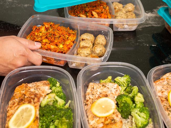 Filipino Man putting away meal prep containers Salmon and Chicken Meat Ball Meal Preps