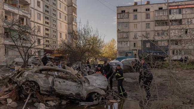 Policemen and emergency personnel check a burned car at the site of the destroyed residential building hit during the Russian attack in Uman. Picture: Roman Pilipey/Getty