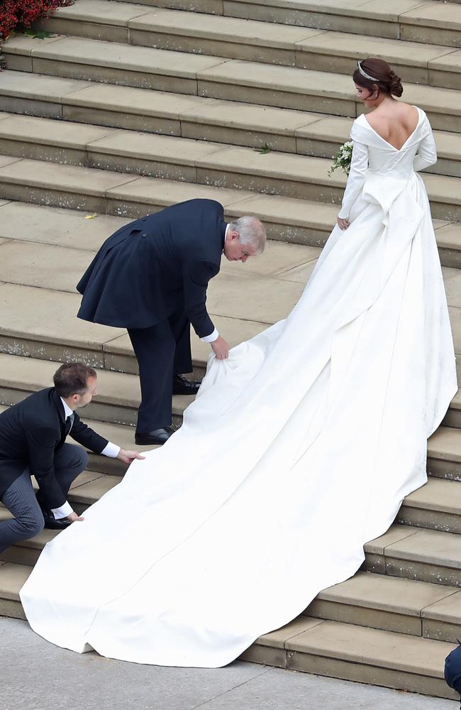 Britain's Prince Andrew, Duke of York (L) adjusts the train of Britain's Princess Eugenie of York (R) as she arrives for her wedding to Jack Brooksbank at St George's Chapel, Windsor Castle, in Windsor, on October 12, 2018. (Photo by Andrew Matthews / POOL / AFP)