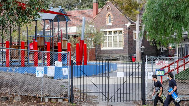 Two youths walk past North Melbourne Primary School, where Covid was transmitted in a classroom. Picture: Tim Carrafa