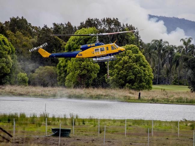 Smoke haze covers the Gold Coast Skyline from a grass fire at Carrara. A firefighting helicopter collects water from Judy Turners property in Carrara . Picture: Jerad Williams