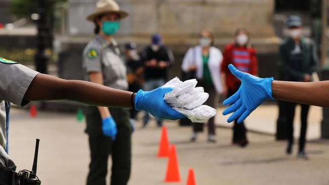 People receive protective masks and bandannas as they are handed out in New York City as face coverings become mandatory. Picture: Spencer Platt/Getty Images/AFP.