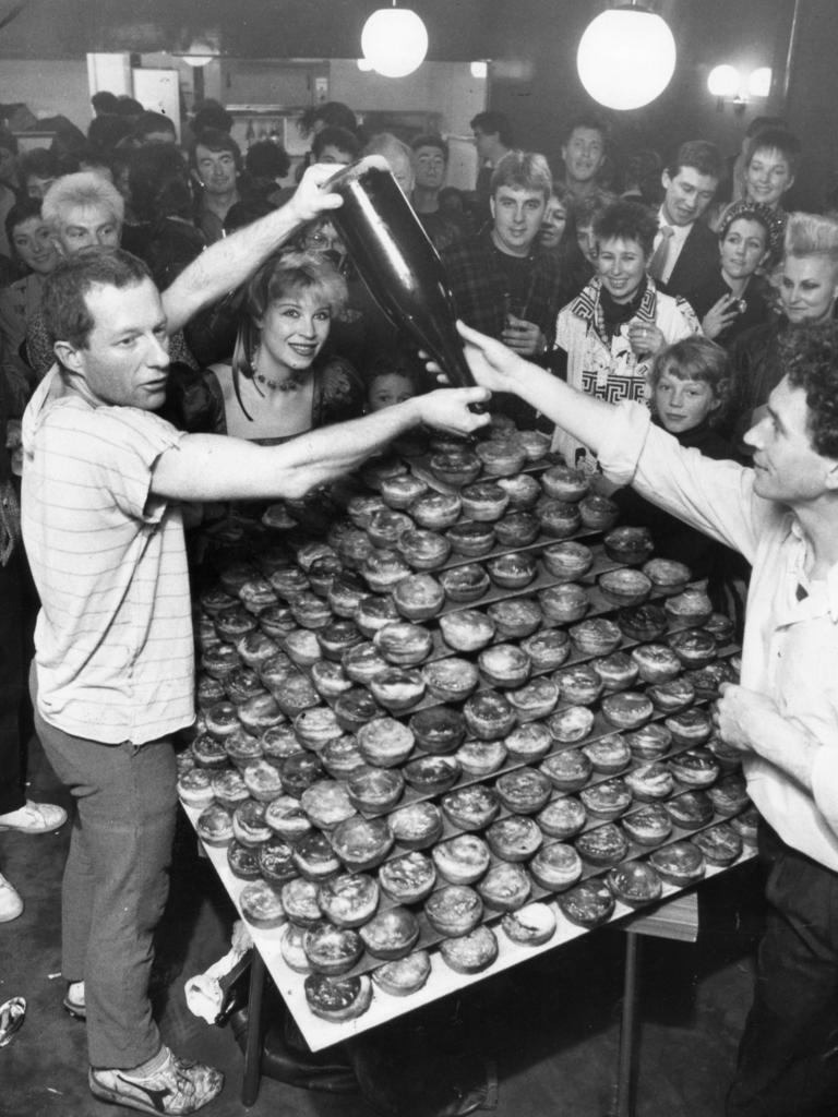 Phillip Searle (left) with Barry Ross pouring sauce on pyramid of pies at farewell dinner for Possums Restaurant in July, 1985.