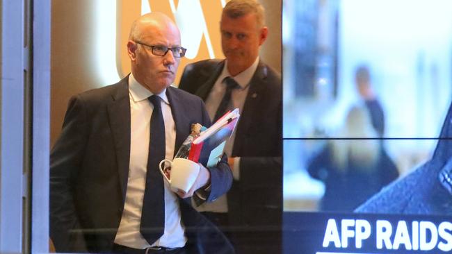 John Lyons (left), Executive Editor of ABC News, is followed by an Australian Federal Police officer as they walk out the main entrance to the ABC building located at Ultimo in Sydney. Picture: AAP/David Gray