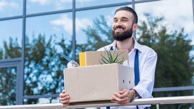 happy businessman with cardboard box with office supplies in hands standing outside office building, quitting job concept. quit job happy. ISTOCK