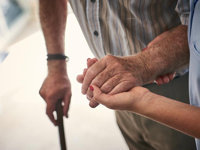 Female nurse supporting senior man to walk. Focus on hands.