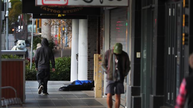 People walk past a homeless man asleep on Scarborough Street. Picture: Glenn Hampson