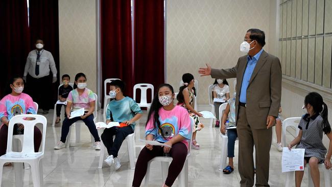 Cambodia's Prime Minister Hun Sen talks to his grandchildren as they wait to receive doses of the Sinovac Covid-19 coronavirus vaccine at the Peace Palace in Phnom Penh.