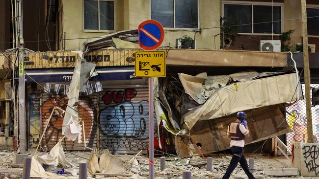 An Israeli rescuer walks in front of a damaged shop in Tel Aviv after it was hit by a rocket fired by Palestinian militants on October 7