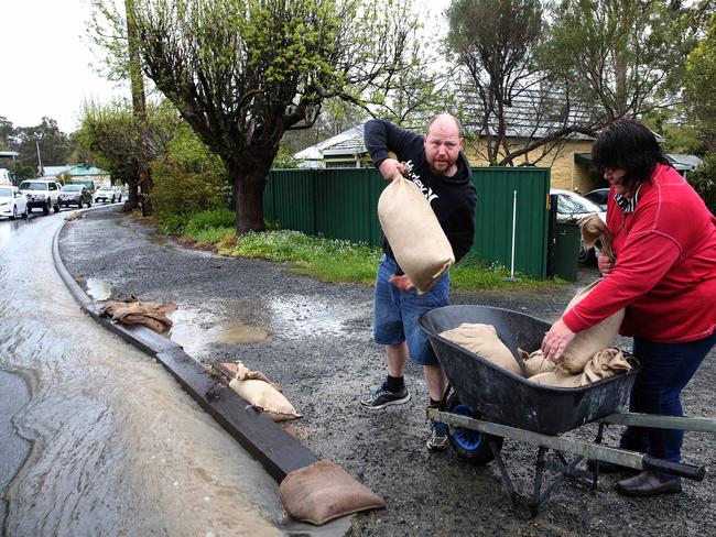 Mark Baryczka helps his neighbour Rebecca Francis sand bagging her driveway in SA. Picture Dean Martin