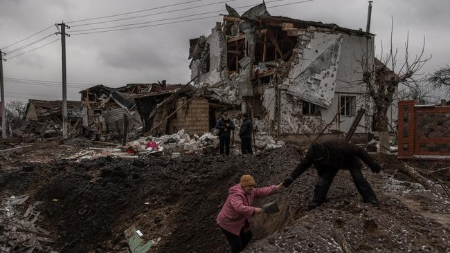 A man helps a woman to get out from a crater next to damaged residential buildings following Russian missile attacks outside Kyiv. Picture: Getty Images.