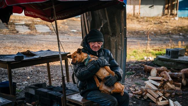 Anatoly Gysenko, 60, hugs a dog in the street outside his damaged home on January 4, 2023, amid the Russian invasion of Ukraine. Krissy Regan says Ukrainians will face sub-zero temperatures during the winter, and many will die without support. (Photo by Dimitar DILKOFF / AFP)