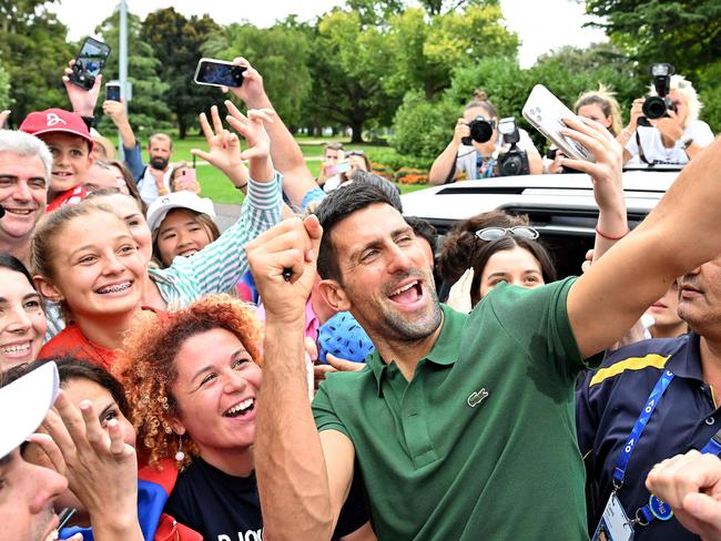 Serbia's Novak Djokovic gets selfies with his supporters outside the Government House  in Melbourne on January 30, 2023, after winning the Australian Open tennis tournament's mens' singles final against Greece's Stefanos Tsitsipas. (Photo by SAEED KHAN / AFP) / -- IMAGE RESTRICTED TO EDITORIAL USE - STRICTLY NO COMMERCIAL USE --