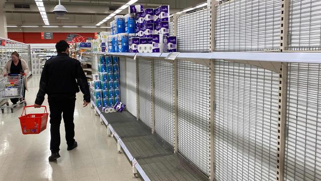 A shopper walks past near-empty shelves of toilet paper at a supermarket in a Melbourne on June 26, 2020. - Supermarkets imposed purchase limits on toilet paper across Australia on June 26 following panic buying by people rattled over a surge in coronavirus cases in the country's second-biggest city. (Photo by William WEST / AFP)