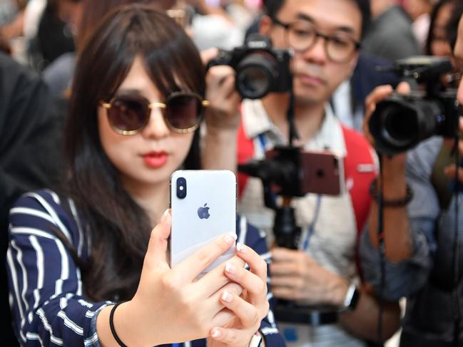 People take photos as a woman tests out a new iPhone X during a media event at Apple's new headquarters in Cupertino, California on September 12, 2017.  / AFP PHOTO / Josh Edelson